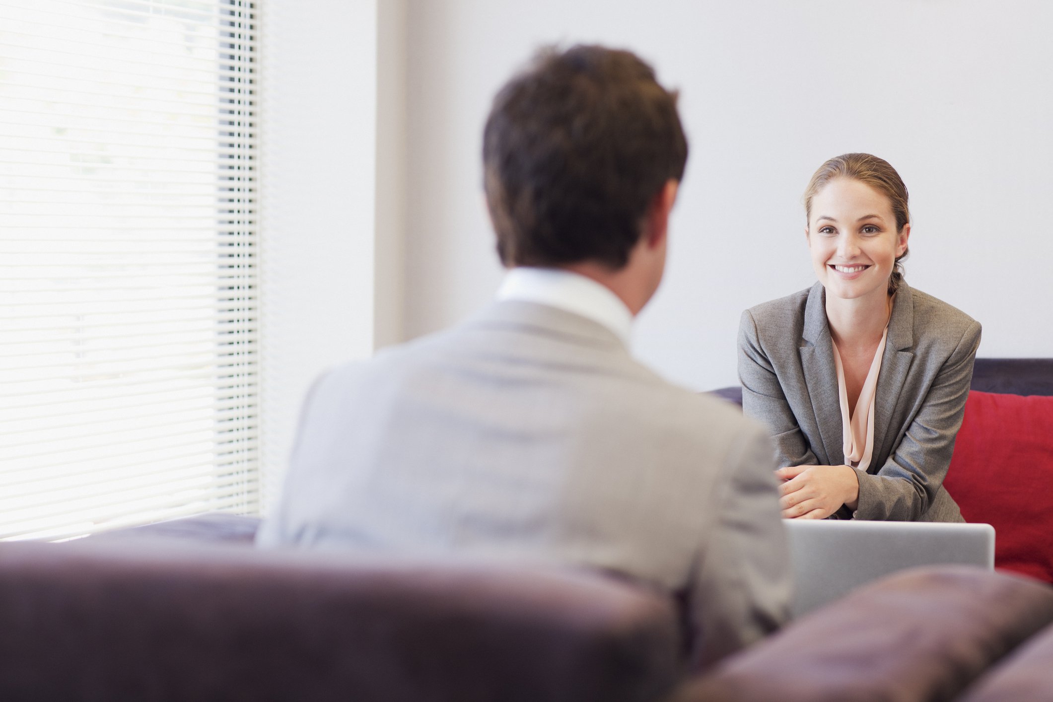 A woman sits across from a man during an interview.