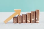 Arrow resting atop ascending wooden blocks with percentage signs also increasing in size written on them.