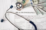 Health insurance paperwork with stethoscope and money on top