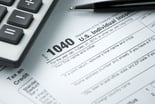 A 1040 tax form with pen and calculator
