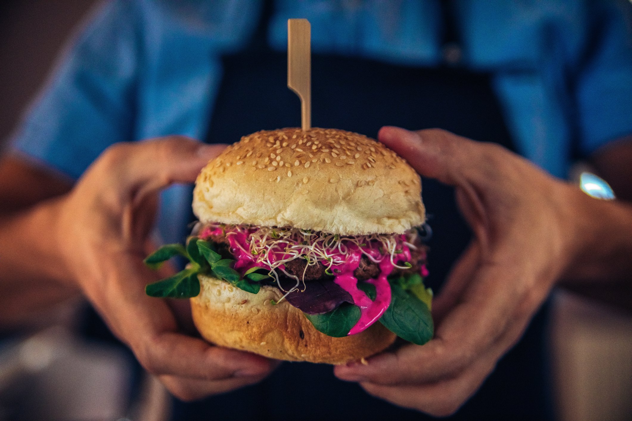 Hands holding a thick veggie burger.
