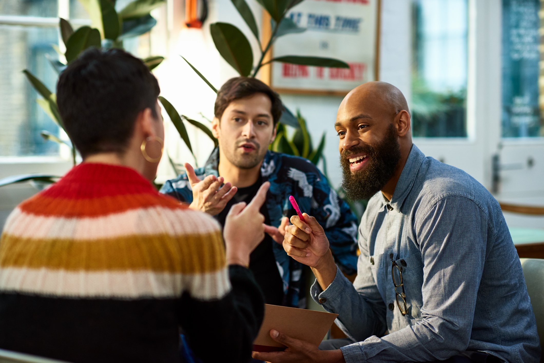 Three people sitting and talking in a colorful setting.