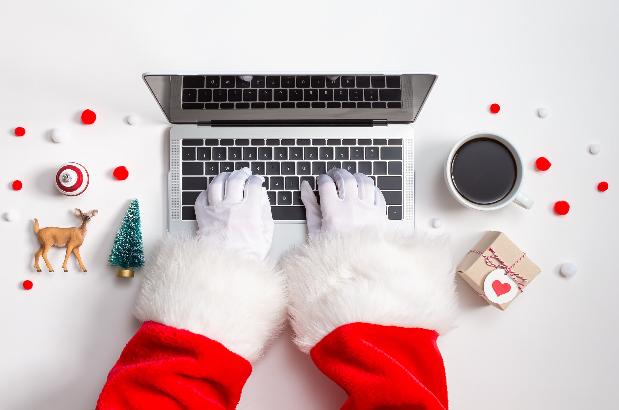 Person dressed in Santa suit with white gloves typing on laptop