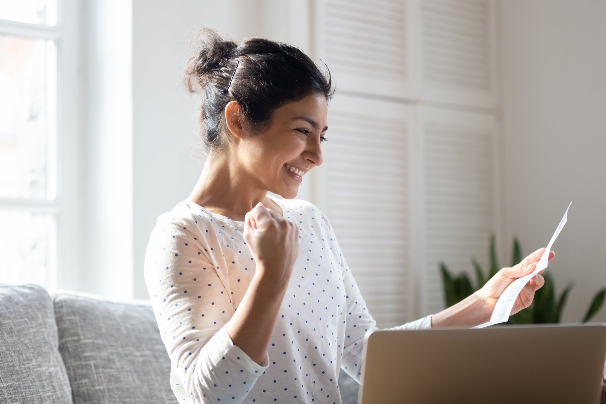 Woman with open laptop looking at financial statement and smiling