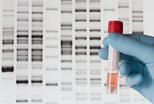 Medical-gloved hand holding human DNA in front of sequence imaging.jpg