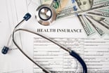 Health insurance document, stethoscope and bills
