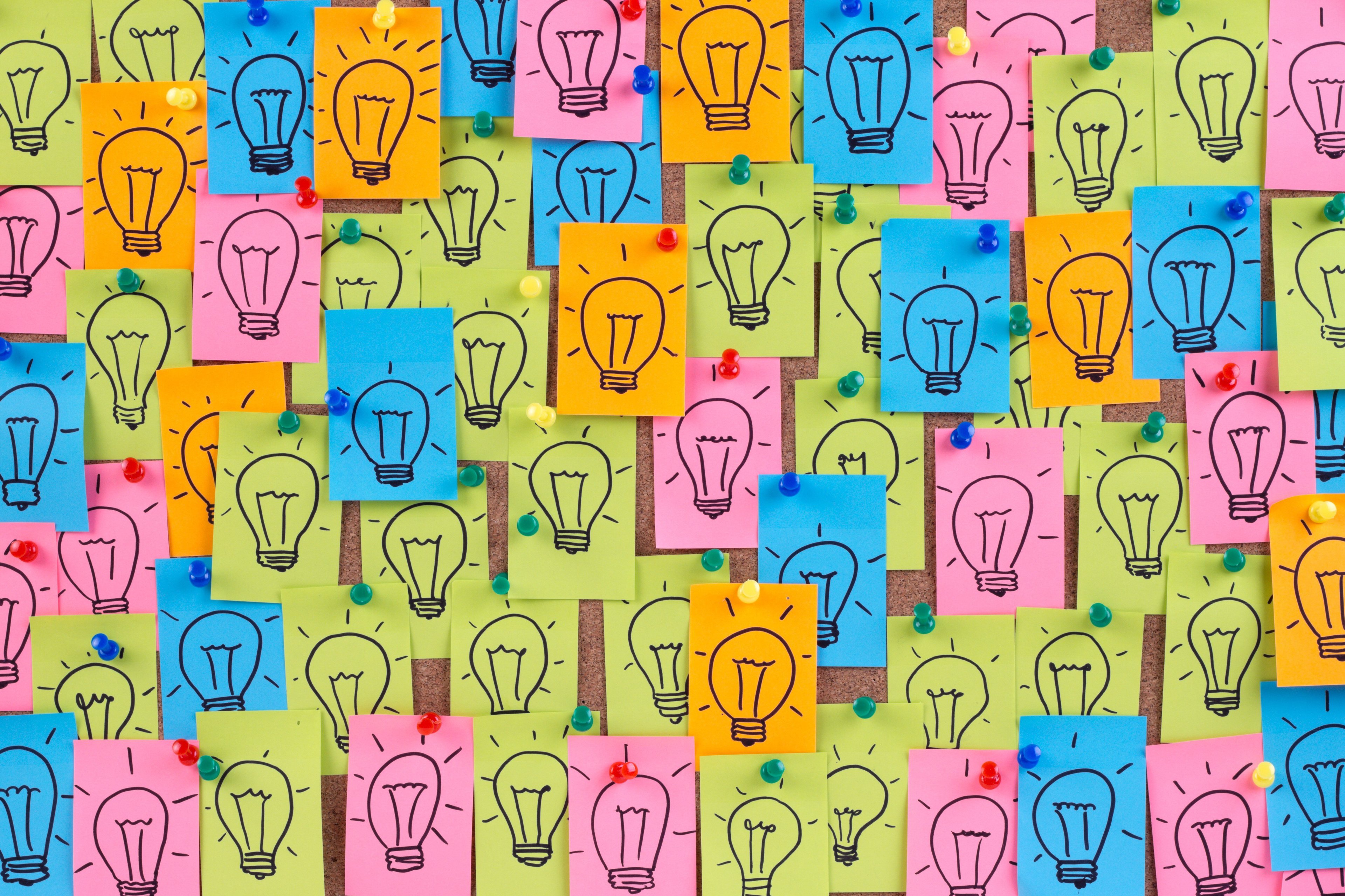Multi colored post it notes with lightbulbs drawn on them.