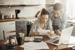 Couple in kitchen reviewing paperwork.