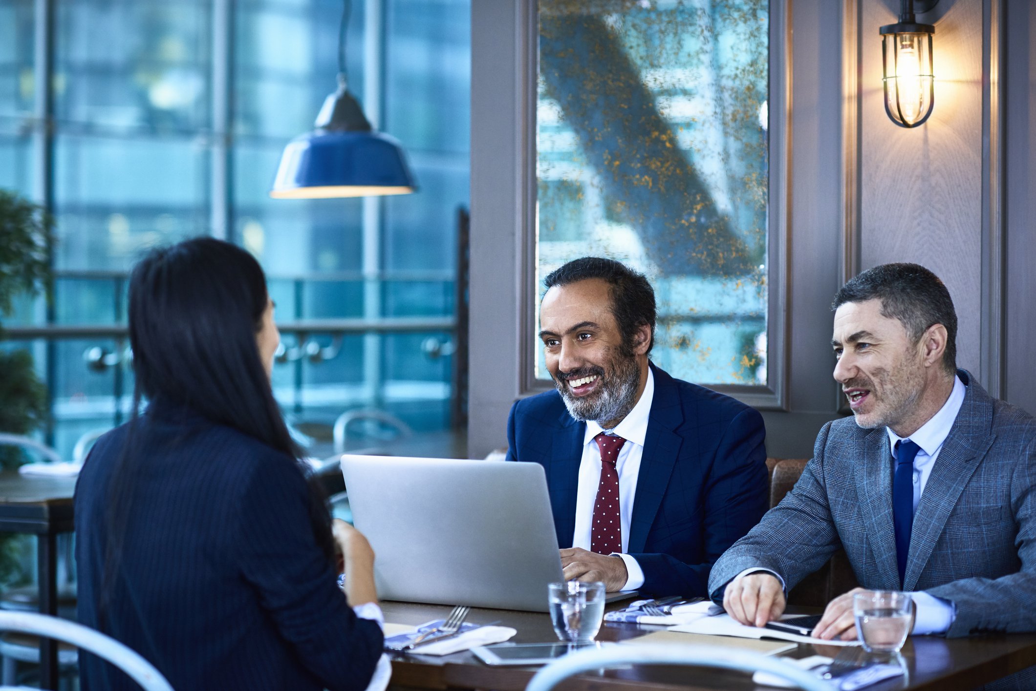 Smiling businesspeople talking and reviewing data on laptop.