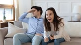 Excited and frustrated people sharing a TV couch