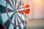 A target with darts in and around the bullseye.