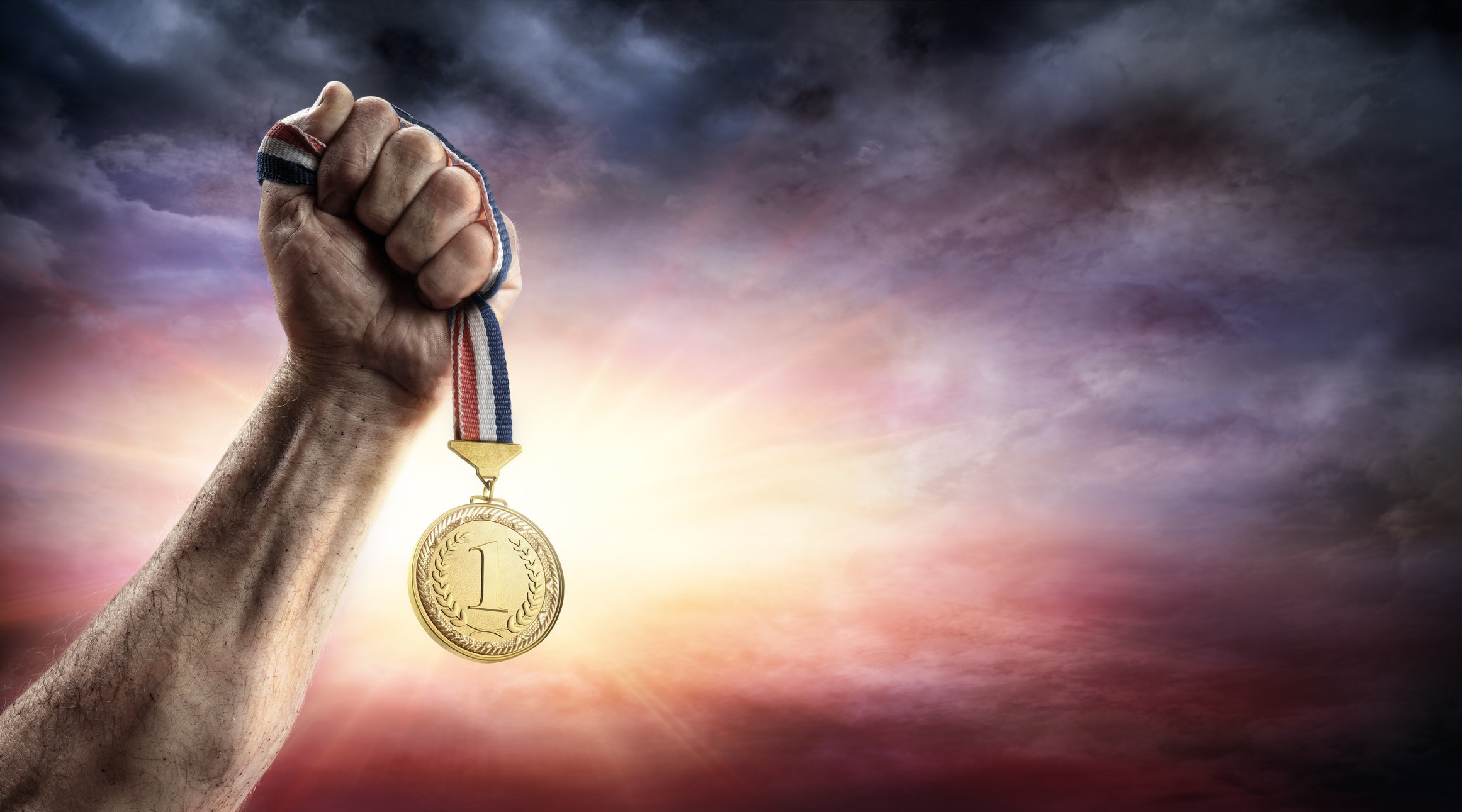 hand hoisting gold medal