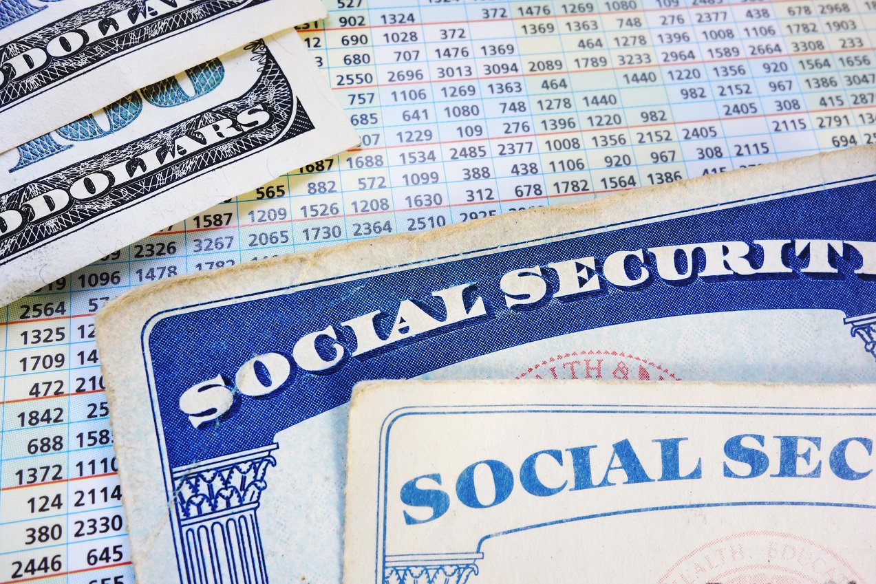 Two Social Security cards and two hundred dollar bills partially covering a payout card