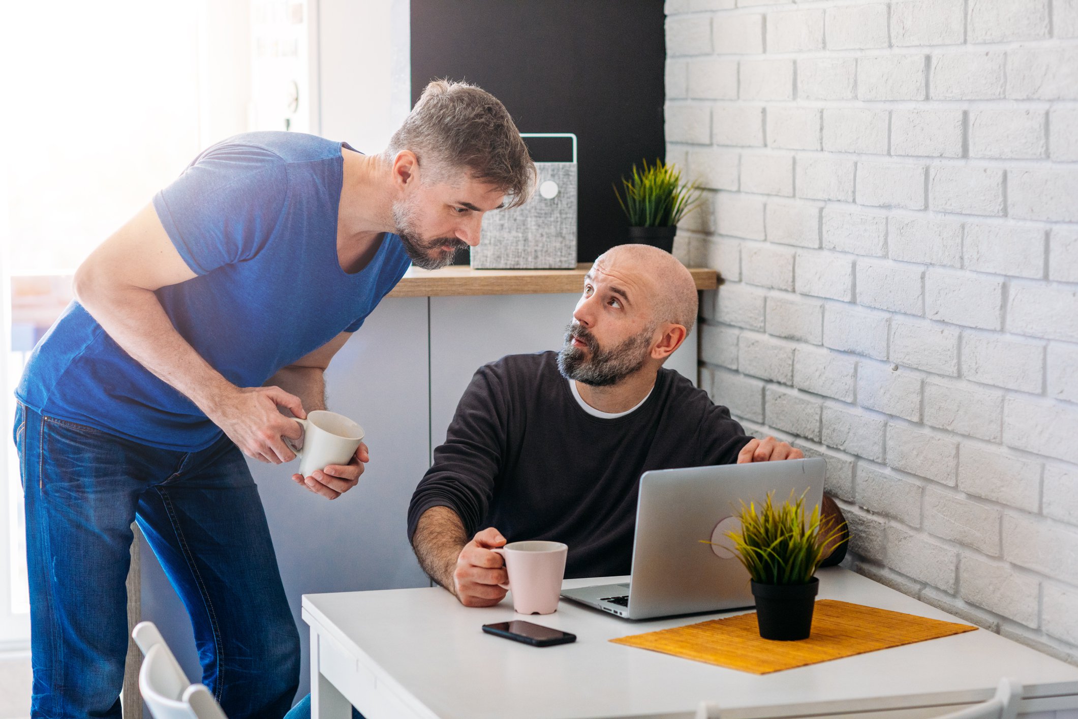 Two people discussing something on laptop screen.