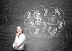 Woman stands in front of chalkboard featuring thought bubble with dollar signs.