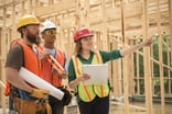 Workers at construction site inside framed building.