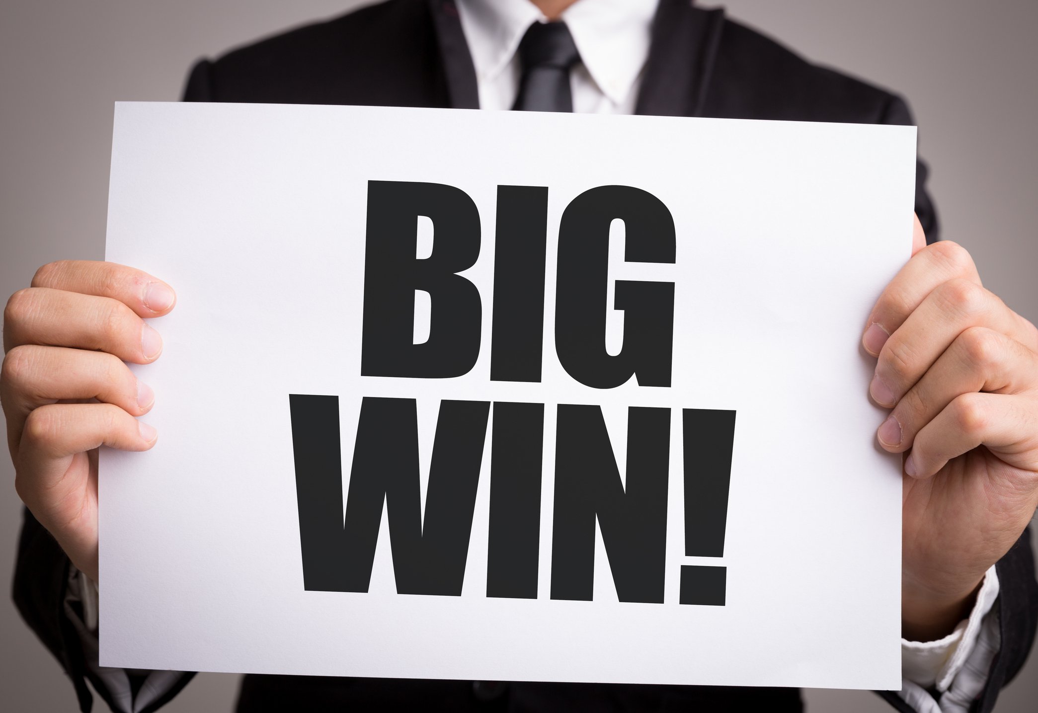 Man holding a sign that reads BIG WIN.