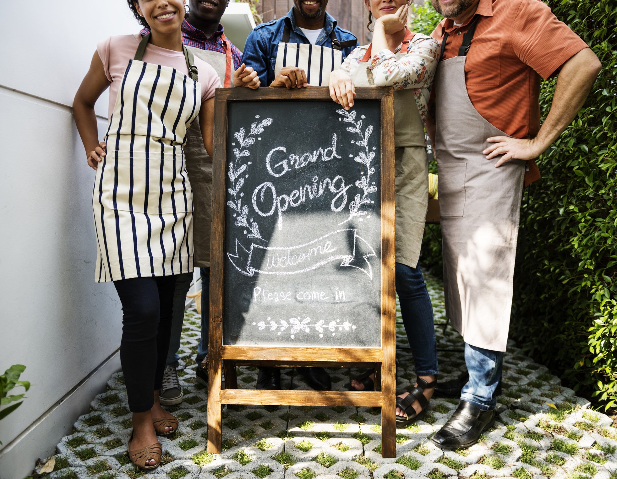 Workers standing by a chalkboard sign reading Grand Opening