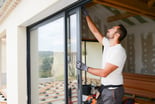 young man installing bay window in a new house construction site
