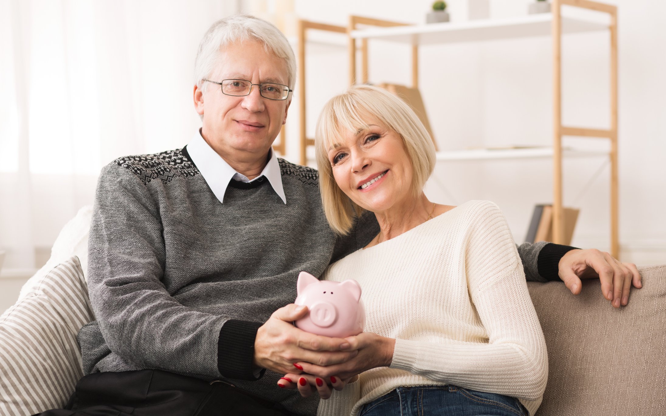 Happy senior couple holding piggy bank