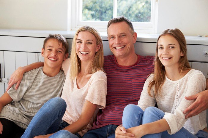Smiling parents and children sitting on a bench.