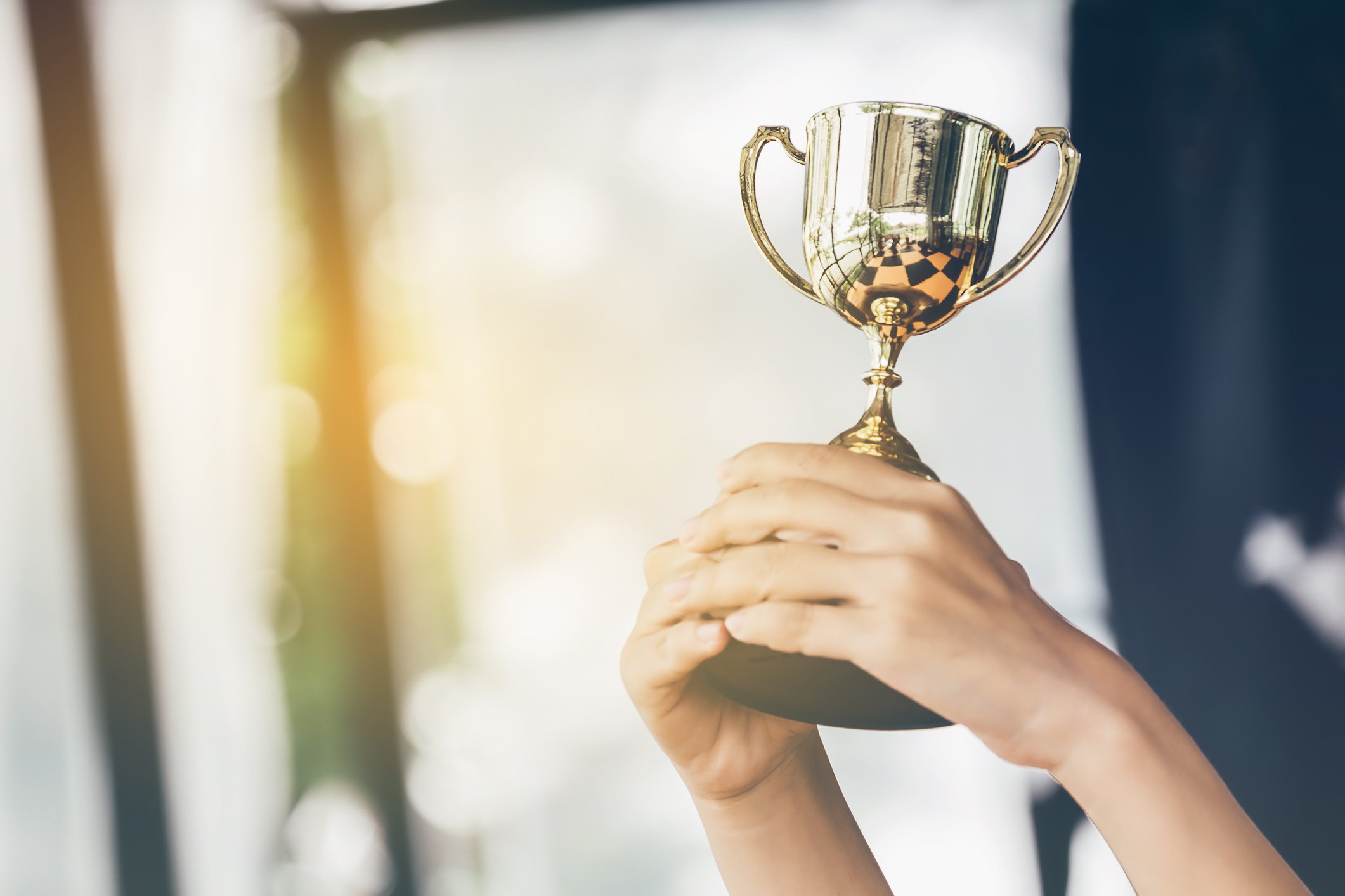 Hand holding up a small golden trophy