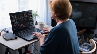 Mature woman looks at stocks on laptop