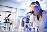 A scientist looking through a microscope.