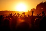 People with their hands in the air at an outdoor concert.