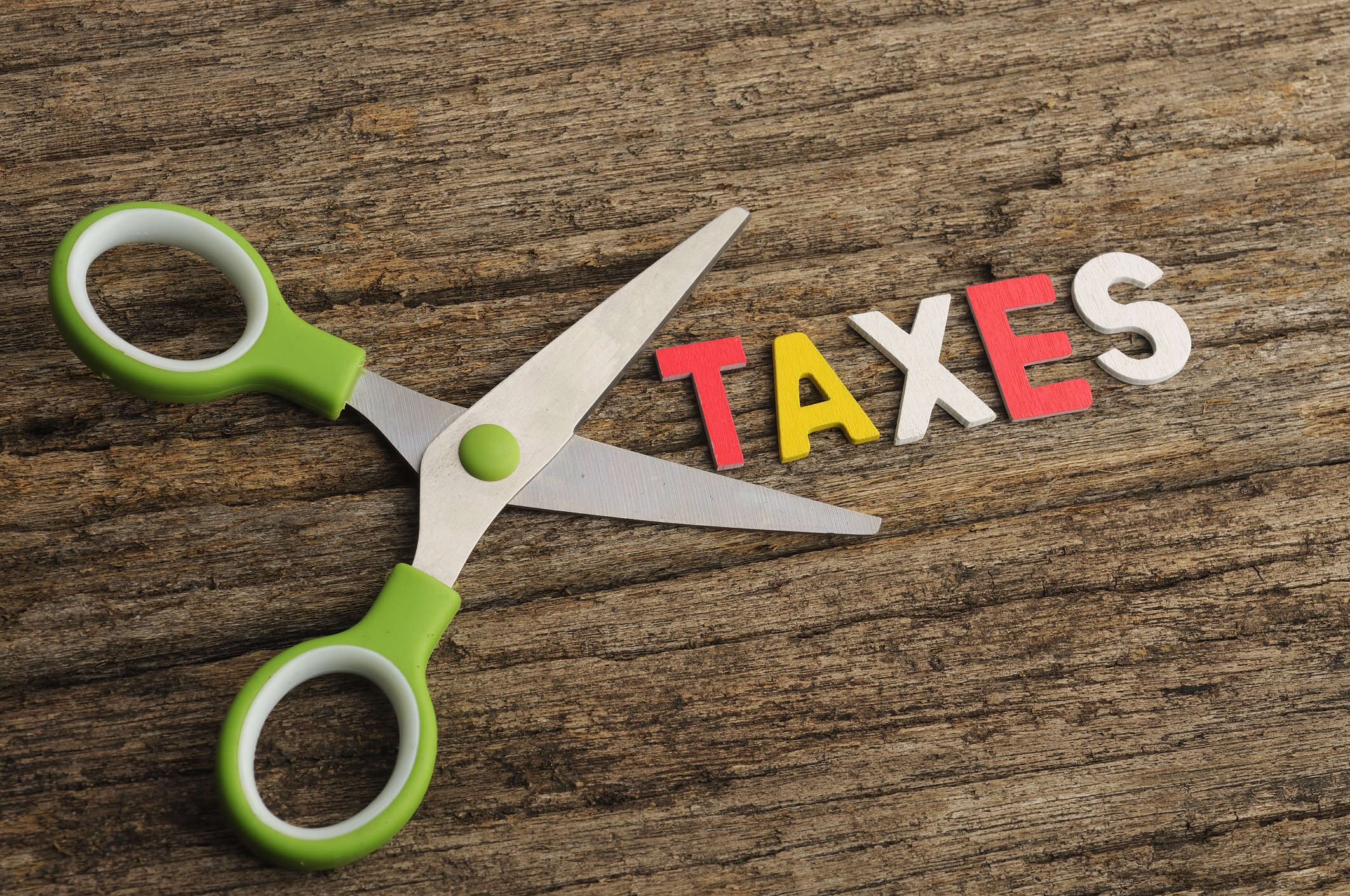 Scissors lying next to word Taxes -- tax cut deduction credit