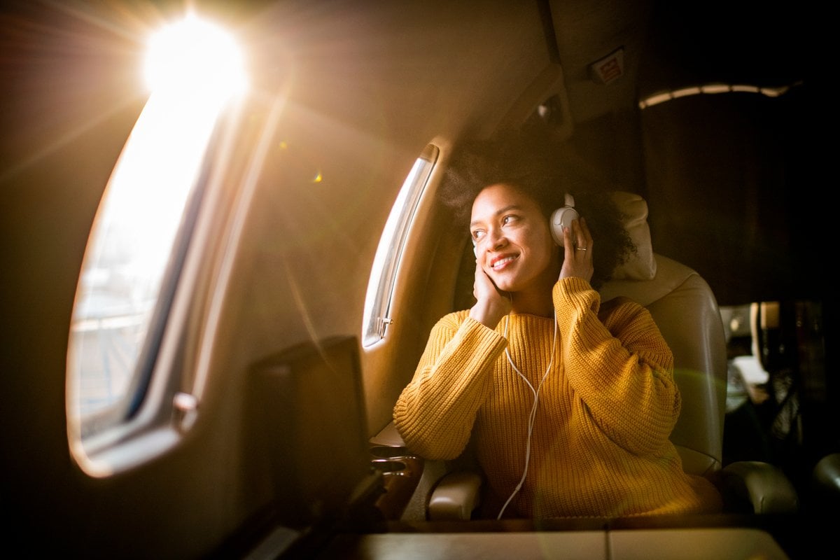 passenger listens to music while on an airplane.
