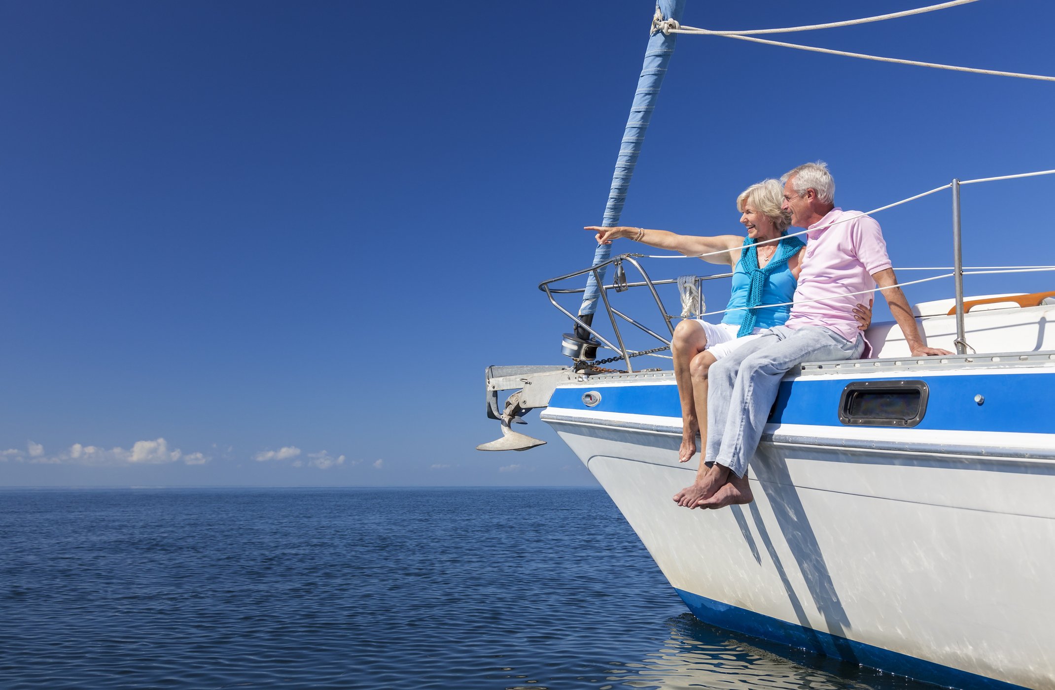 senior couple on sailboat wife pointing toward horizon