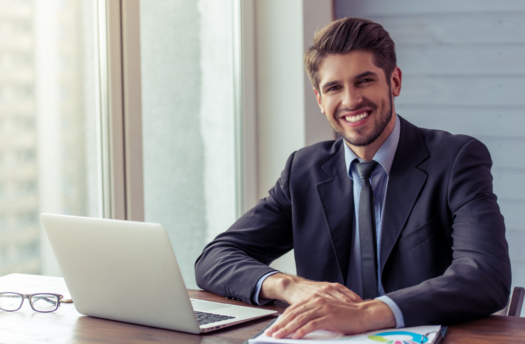 Smiling man in business suit at laptop.