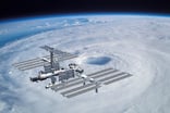 the international space station floating in orbit over clouds.