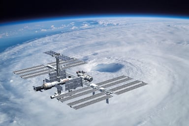 the international space station floating in orbit over clouds.