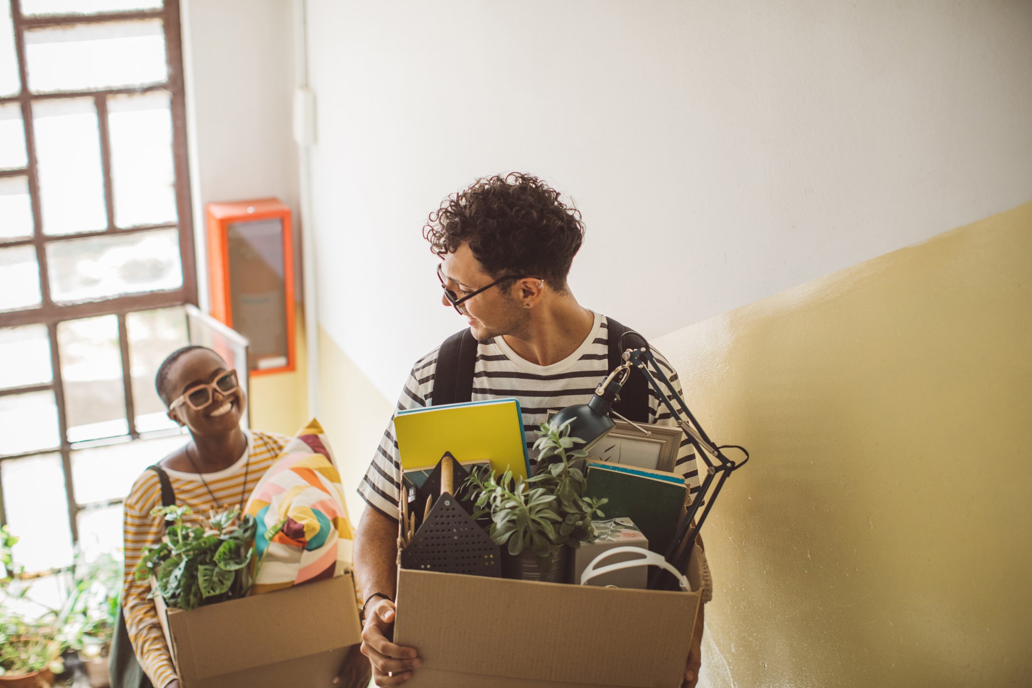 two people moving in, scaling steps with boxes
