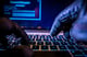 pair of gloved hands typing on laptop keyboard -- hacker cyber attack