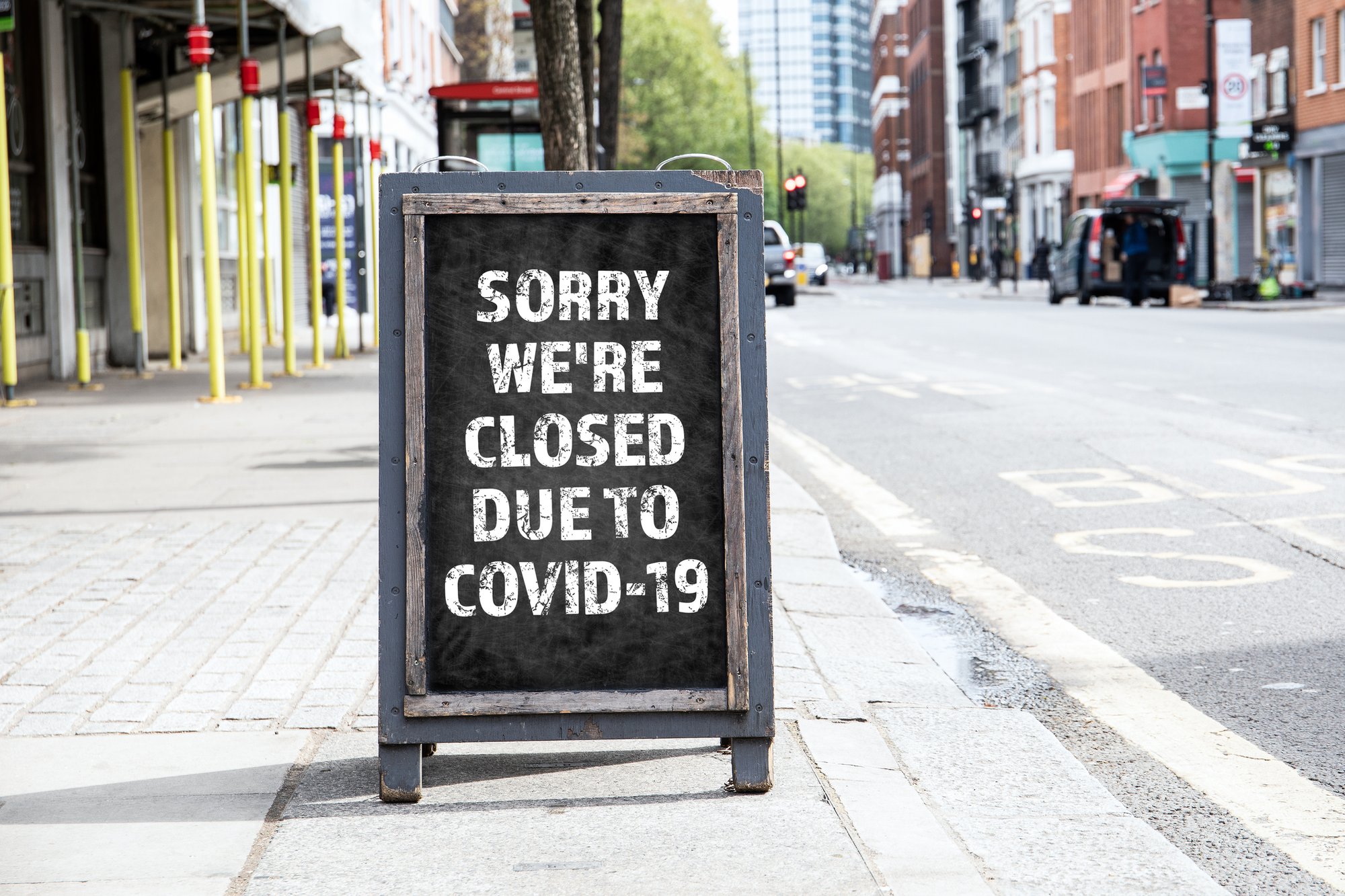 A foldable sign in front of a store that reads, Sorry We're Closed Due to COVID-19.