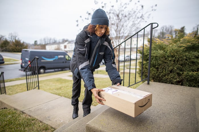 An Amazon employee delivering a package on someone's doorstep.