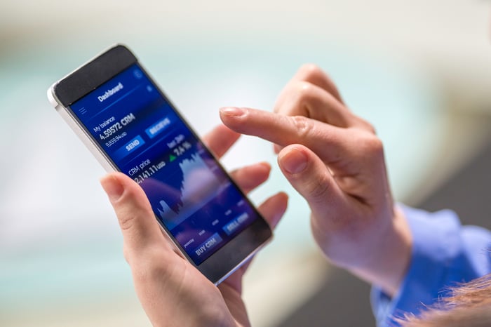 A person submitting a stock order on a mobile device.